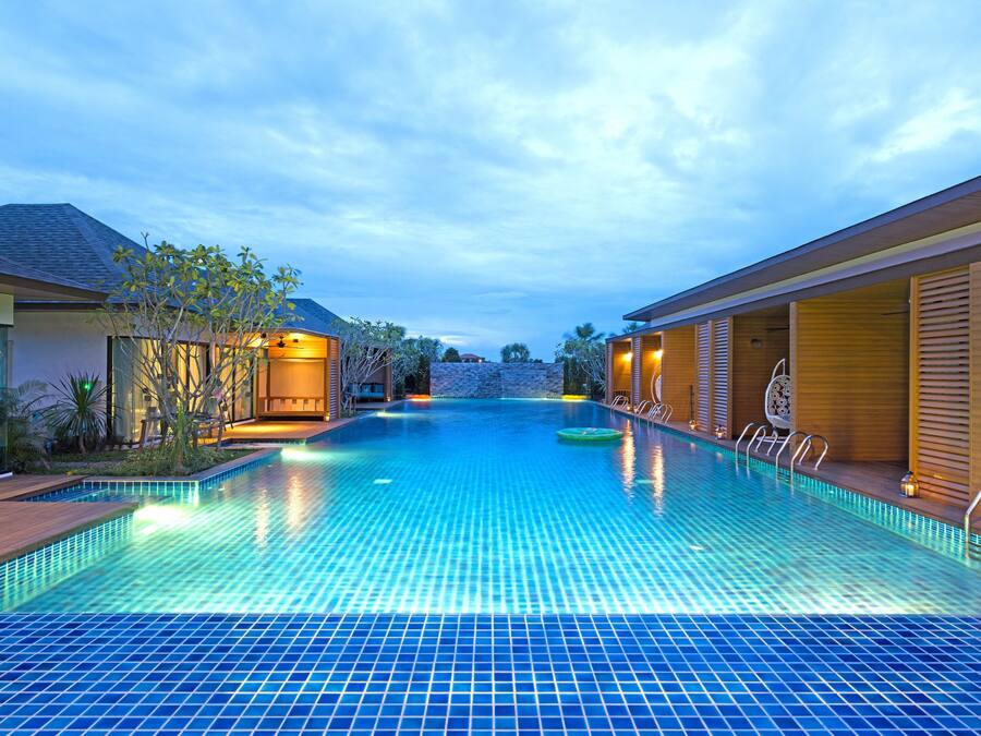 Una piscina con suelo de baldosas, rodeada de edificios de madera con ventanas y puertas.