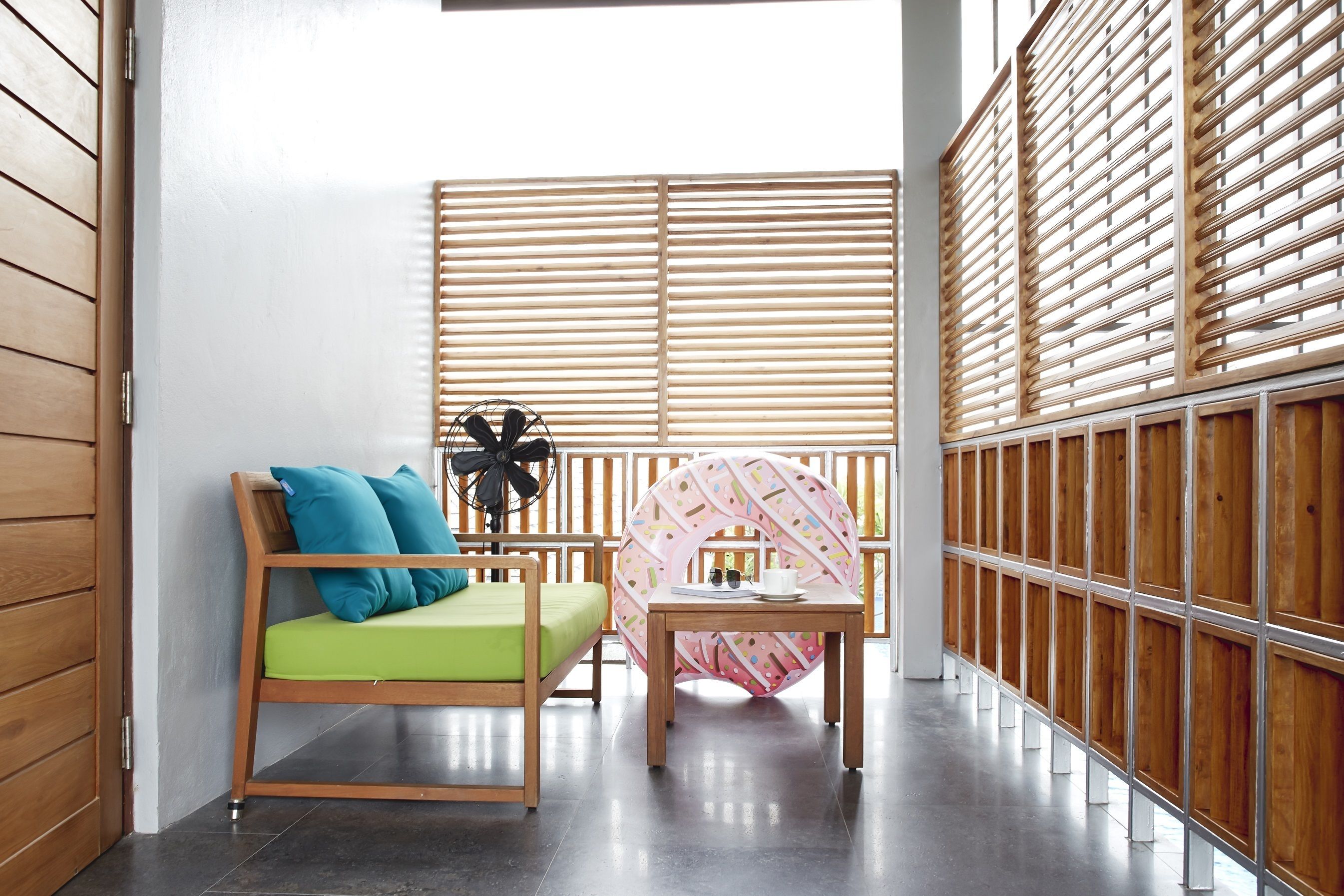 A small, cozy room with a wooden bed, a green cushion, a small table, and a decorative wall panel.