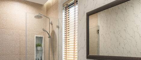 A modern bathroom with a glass-enclosed shower, a white toilet, a marble sink, and a large mirror.