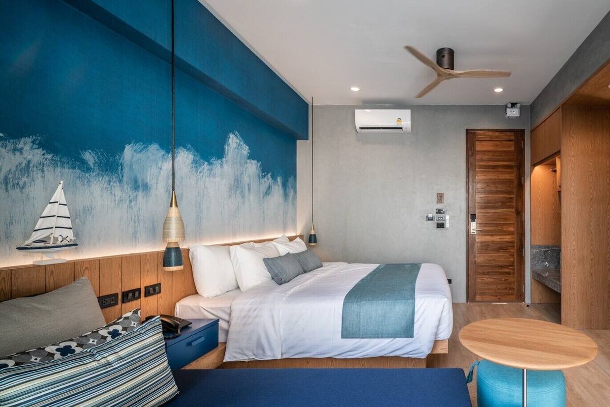 Ein modernes Hotelzimmer mit einem Bett, einem kleinen runden Tisch, einem Fernseher und einem großen Fenster mit Meerblick.