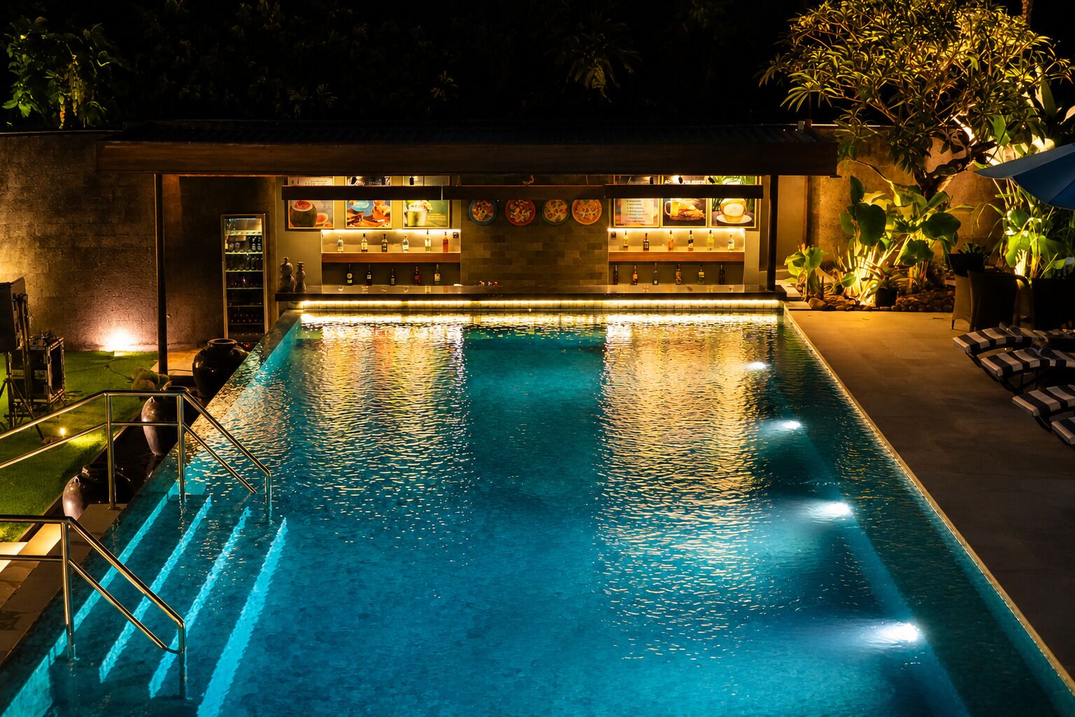 A swimming pool with a bar area, lounge chairs, and potted plants.