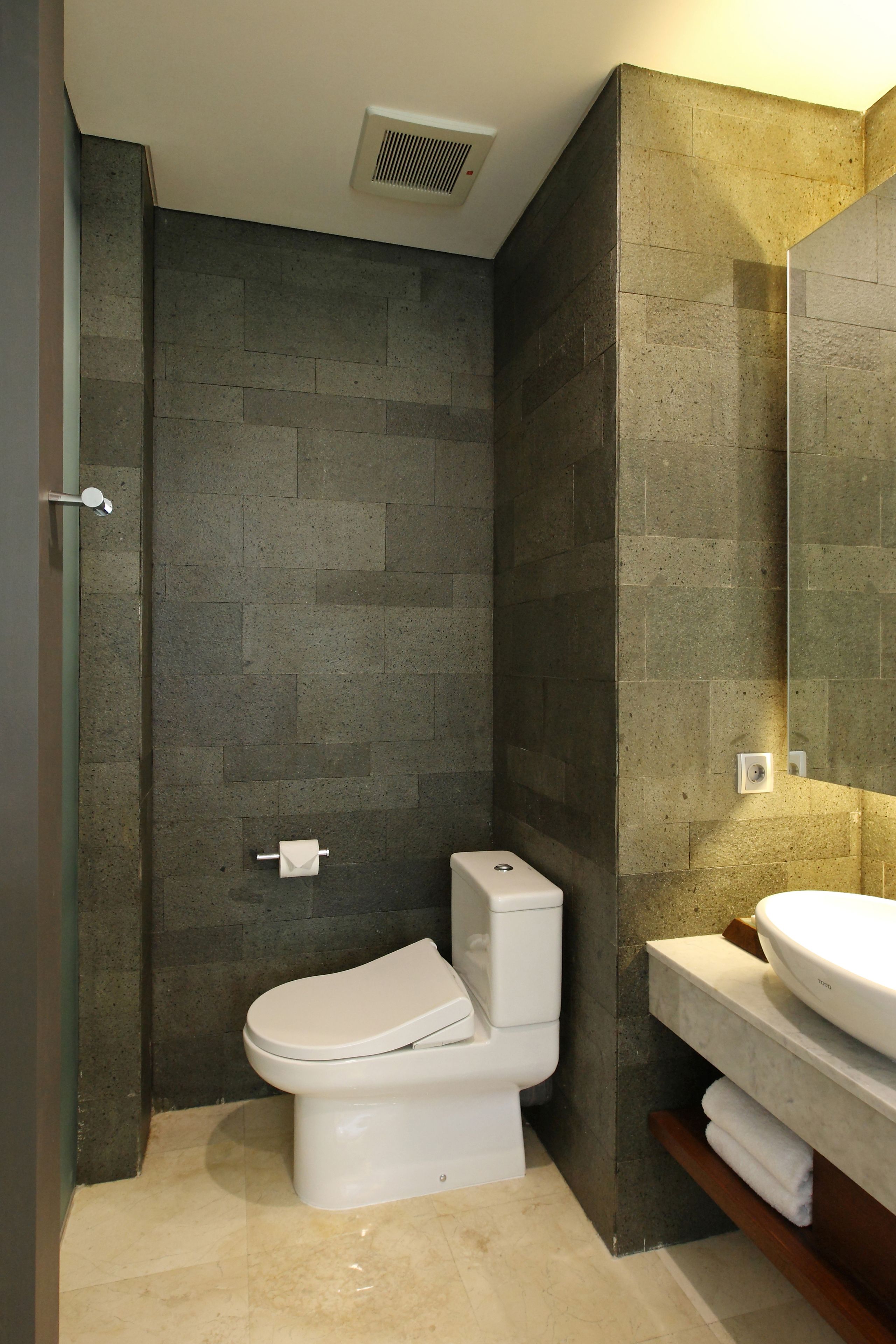 Un bagno moderno con toilette, lavabo e specchio.