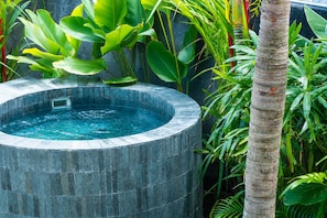 Un jacuzzi de piedra circular rodeado de exuberante vegetación tropical.