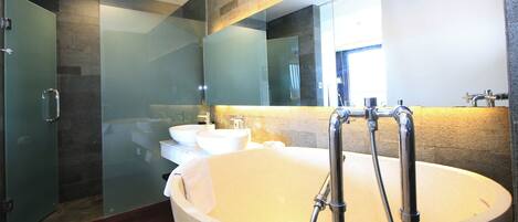 A modern bathroom with a large bathtub, two sinks, and a glass shower enclosure.