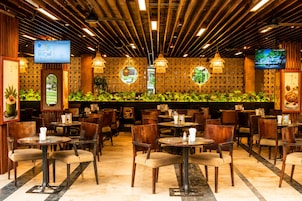 Un restaurante con varias mesas y sillas, techo de madera y una pared con una pantalla mostrando un menú.