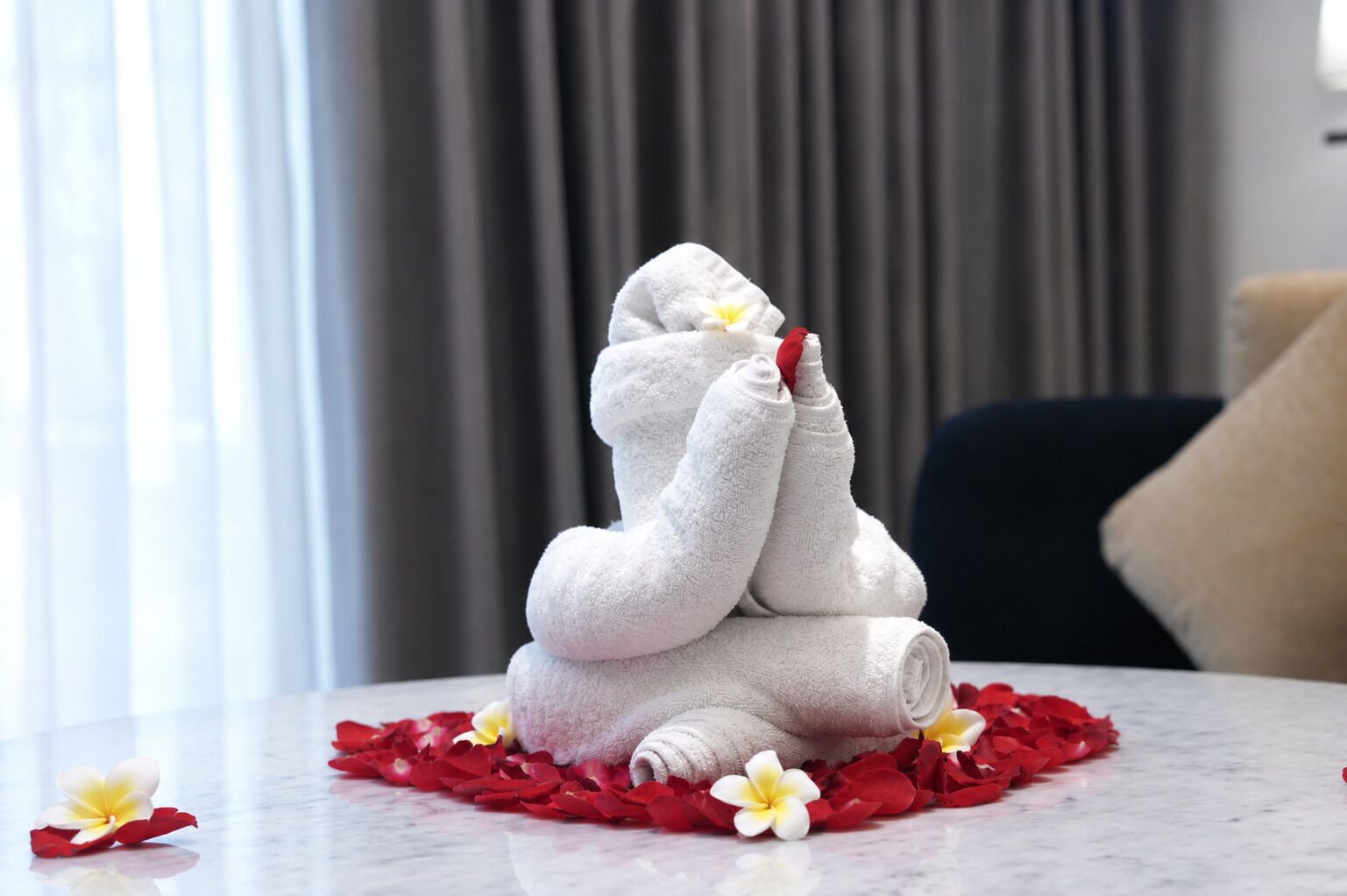 Eine Handtuchskulptur auf einer Marmorplatte mit roten und weißen Blumen.