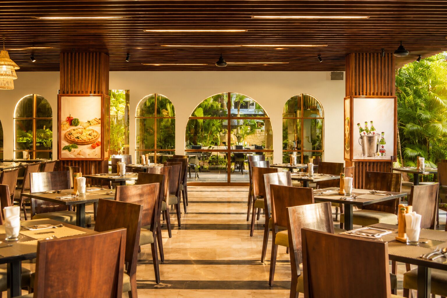 Un restaurante con una zona de comedor central, ventanas amplias y vistas a zonas verdes.