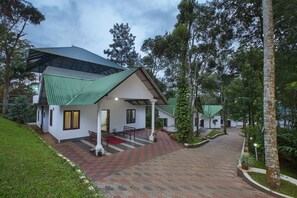 A building with a green roof, a red and grey patterned walkway, and a bench outside. - Misty Lake Resort (Devikolam)