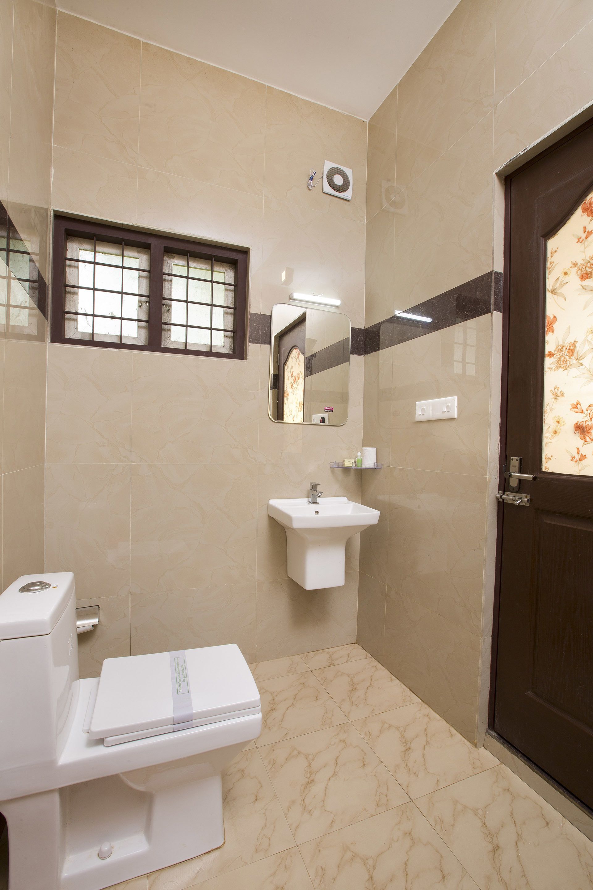 A bathroom with a toilet, sink, mirror, and a window with bars.