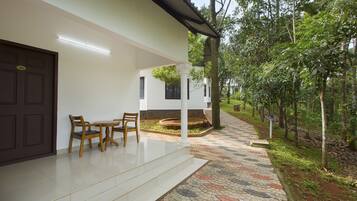 A clean, modern building with a white exterior, a tiled entrance, and a small outdoor seating area with wooden chairs.