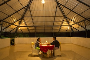 A covered outdoor dining area with a table set for two, under a metal roof structure. - Misty Lake Resort (Devikolam)