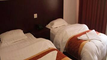 A hotel room with two single beds, a wooden headboard, a nightstand, and a red curtain.