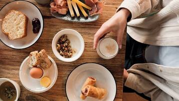 Une table en bois dressée pour le petit-déjeuner, avec divers aliments et un verre de lait.