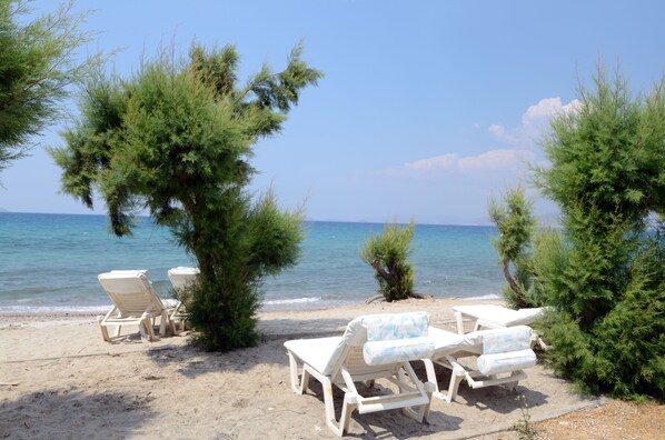 A beach with white lounge chairs and a clear view of the sea. - Byron Apartments (Kos)