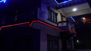 A two-story house with a balcony, illuminated by blue and red lights. - Dipankara Holiday Home (Kathmandu)