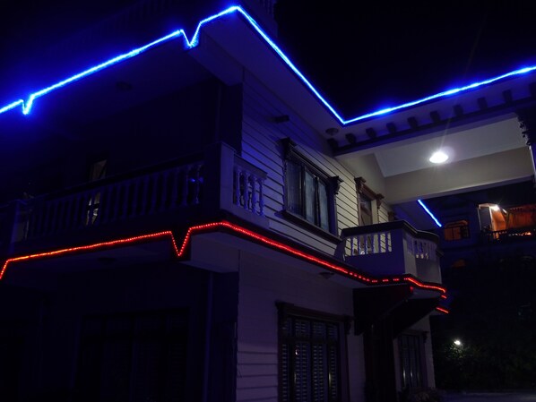 Una casa de dos pisos con un balcón, iluminada con luces azules y rojas.