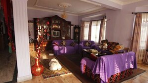 A living room with purple furniture, a wooden cabinet, and a red vase. - Dipankara Holiday Home (Kathmandu)