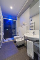 Un baño moderno con ducha de vidrio, bañera blanca y lavamanos doble.