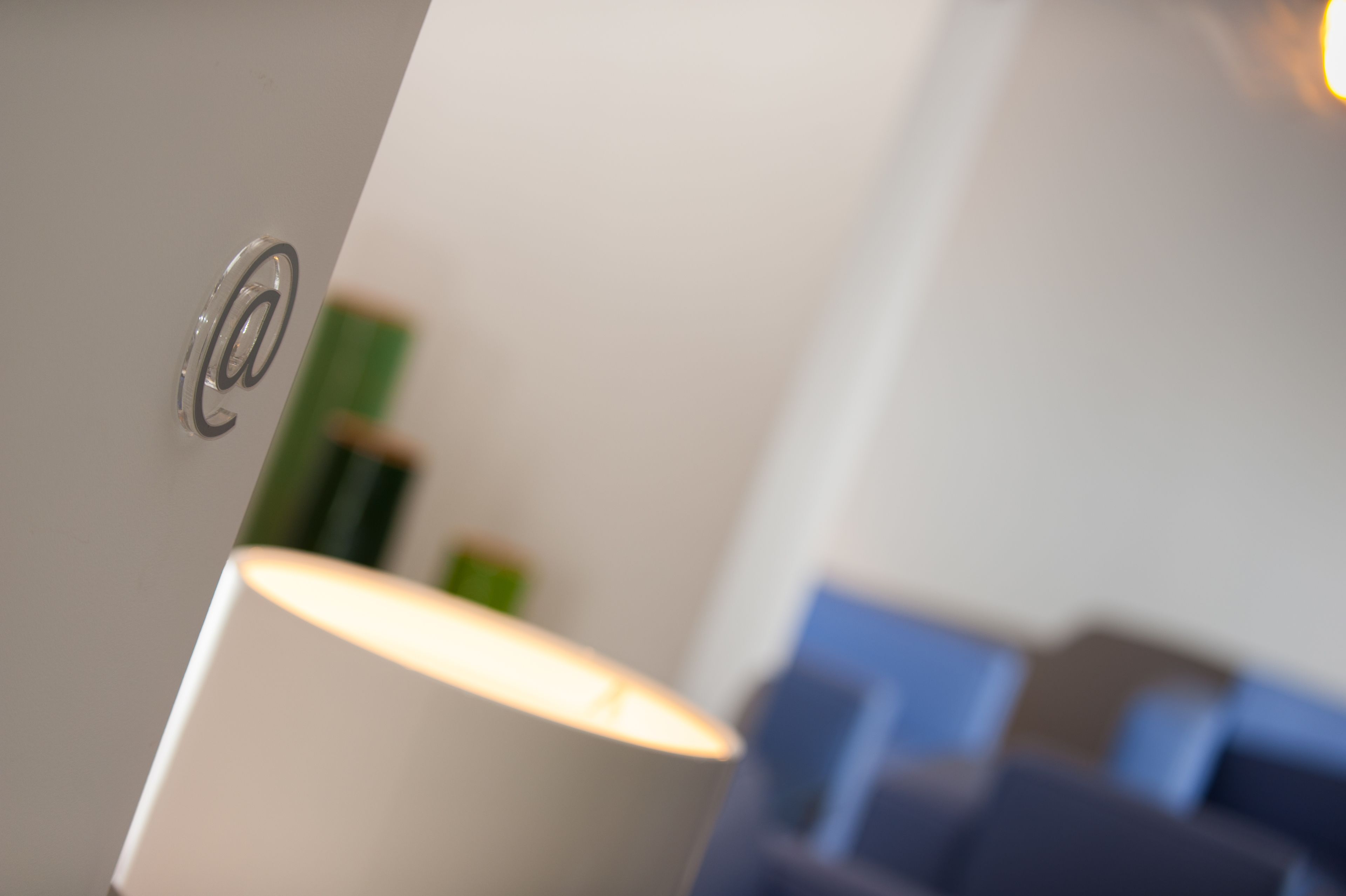 Een detail van een lamp met een metalen voet en een witte lampenkap.