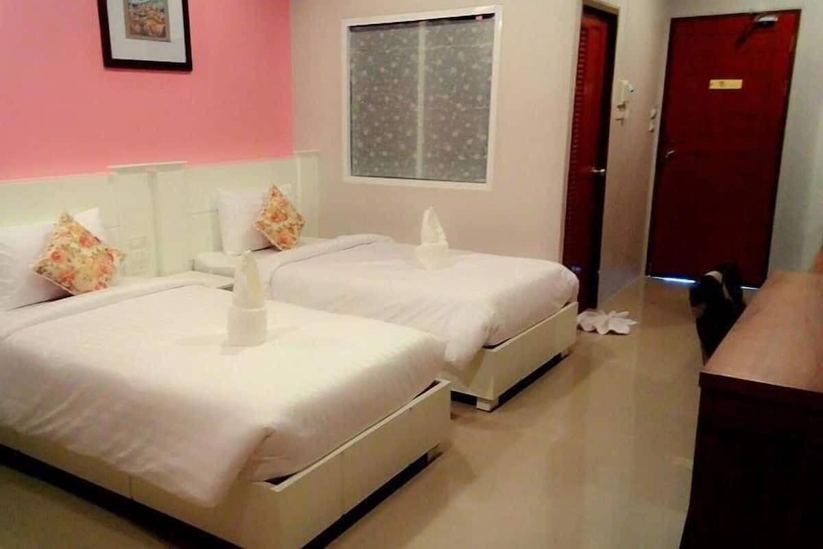 A hotel room with two beds, a window, a door, and a small table.