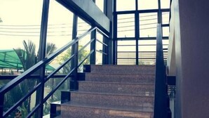 Un escalier avec des rampes en métal menant à un palier, lequel est entouré de grandes fenêtres.