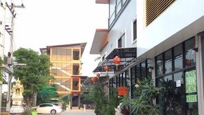 Un hôtel doté d’une façade moderne, d’une entrée bien visible et d’un parking délimité par des cônes de signalisation orange.