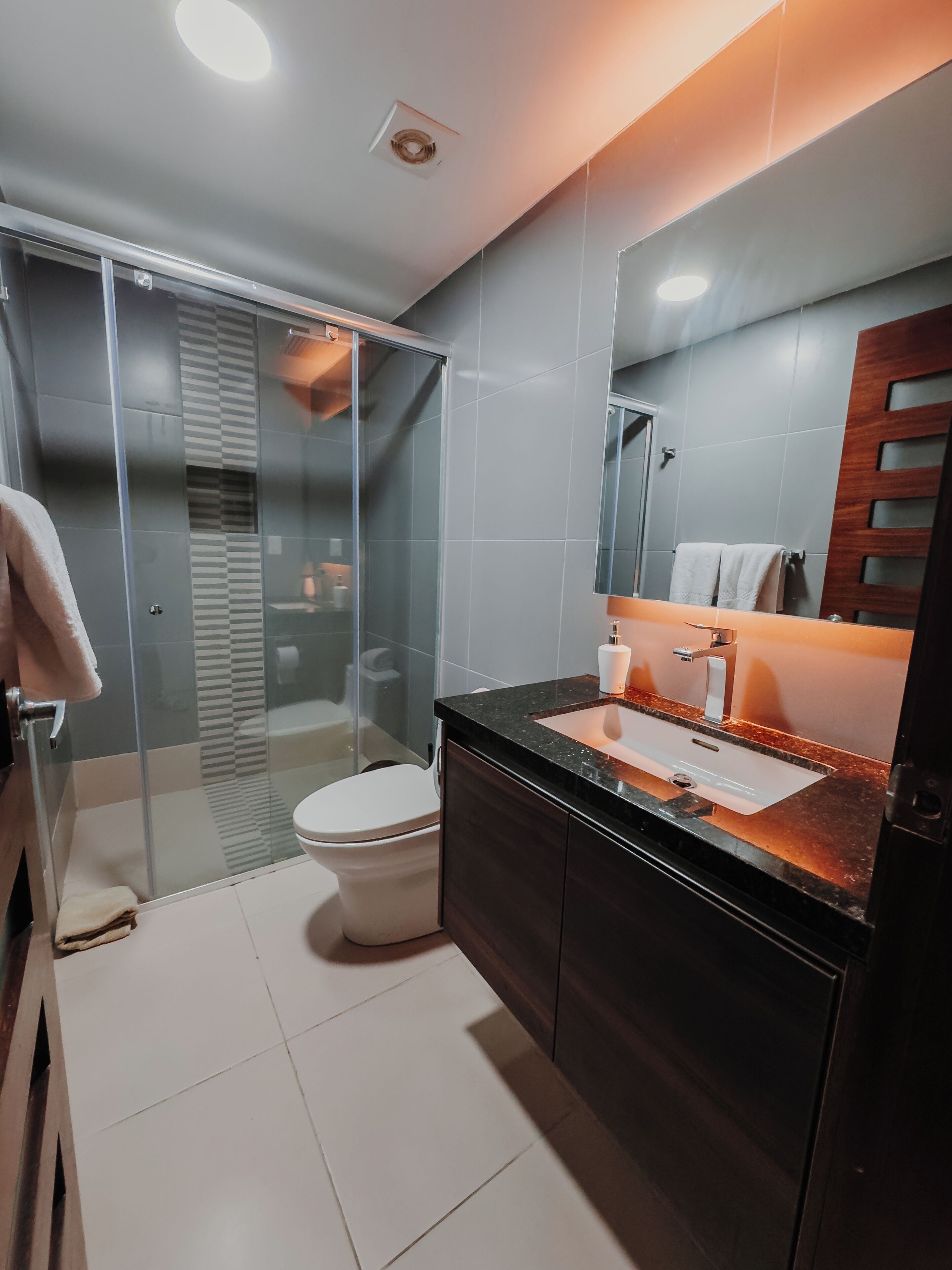 A modern bathroom with a glass shower enclosure, a white toilet, and a dark wood vanity with a sink.