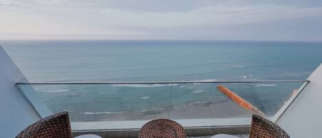 A balcony with wicker furniture and a view of the ocean.
