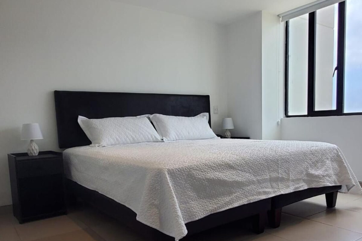 A bedroom with a bed, nightstands, and a window.