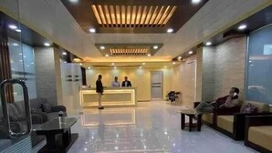 Un vestíbulo de hotel moderno con mostrador de recepción, zona de estar y un panel de vidrio.