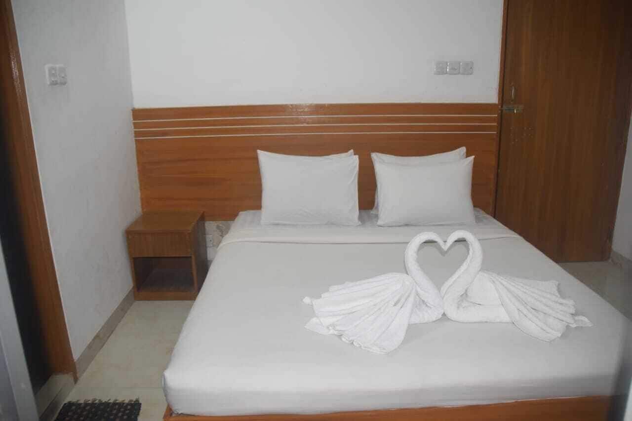 Una cama impecable con ropa blanca y una disposición de toallas en forma de corazón.