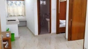Un pasillo estrecho que conduce a un baño con lavamanos y ducha.