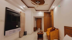 Una sala de estar moderna con una televisión de pantalla plana montada en la pared, un mueble de madera, un ventilador de techo y un sofá.
