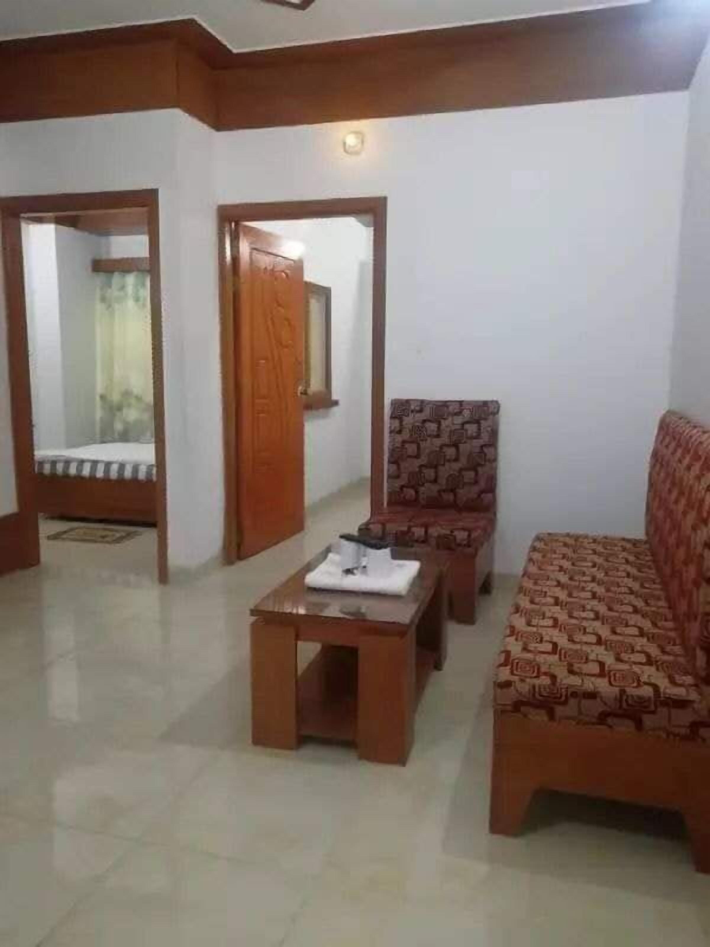 A living room with a sofa, two armchairs, a coffee table, and a door leading to another room.