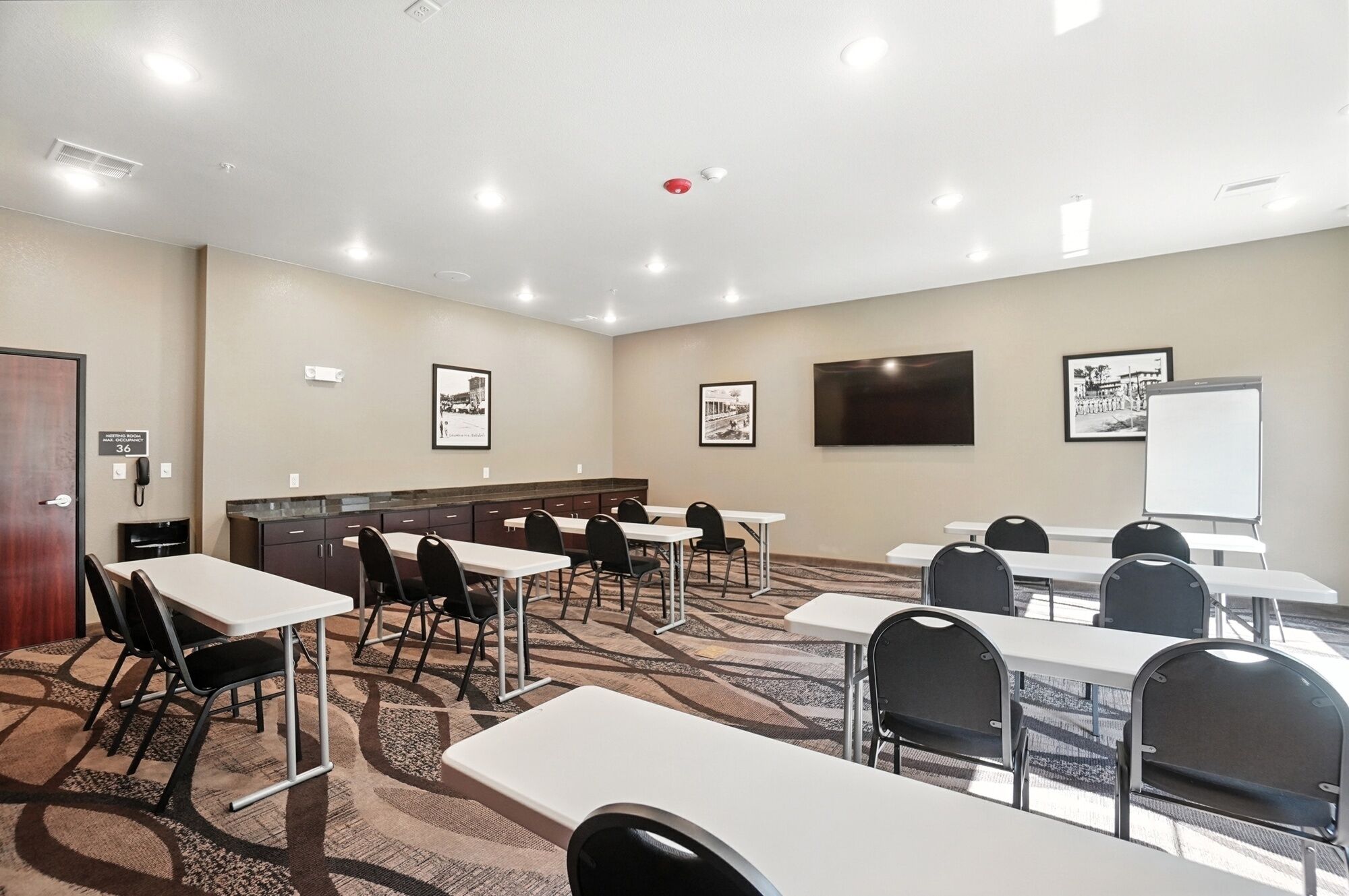 Een vergaderruimte met tafels, stoelen, een whiteboard en ingelijste foto’s aan de muur.