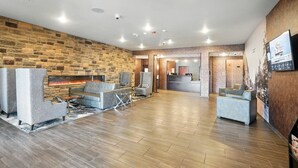 A spacious lobby with a stone wall, a fireplace, and a reception desk. - Cobblestone Hotel & Suites-Bellefontaine (Bellefontaine)