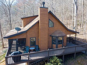 A cabin with a deck, a chimney, and a satellite dish.
