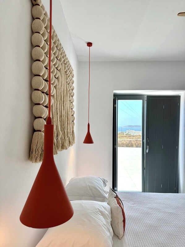 Une chambre avec un lit, une lampe suspendue rouge, une décoration murale et une vue à travers une porte.