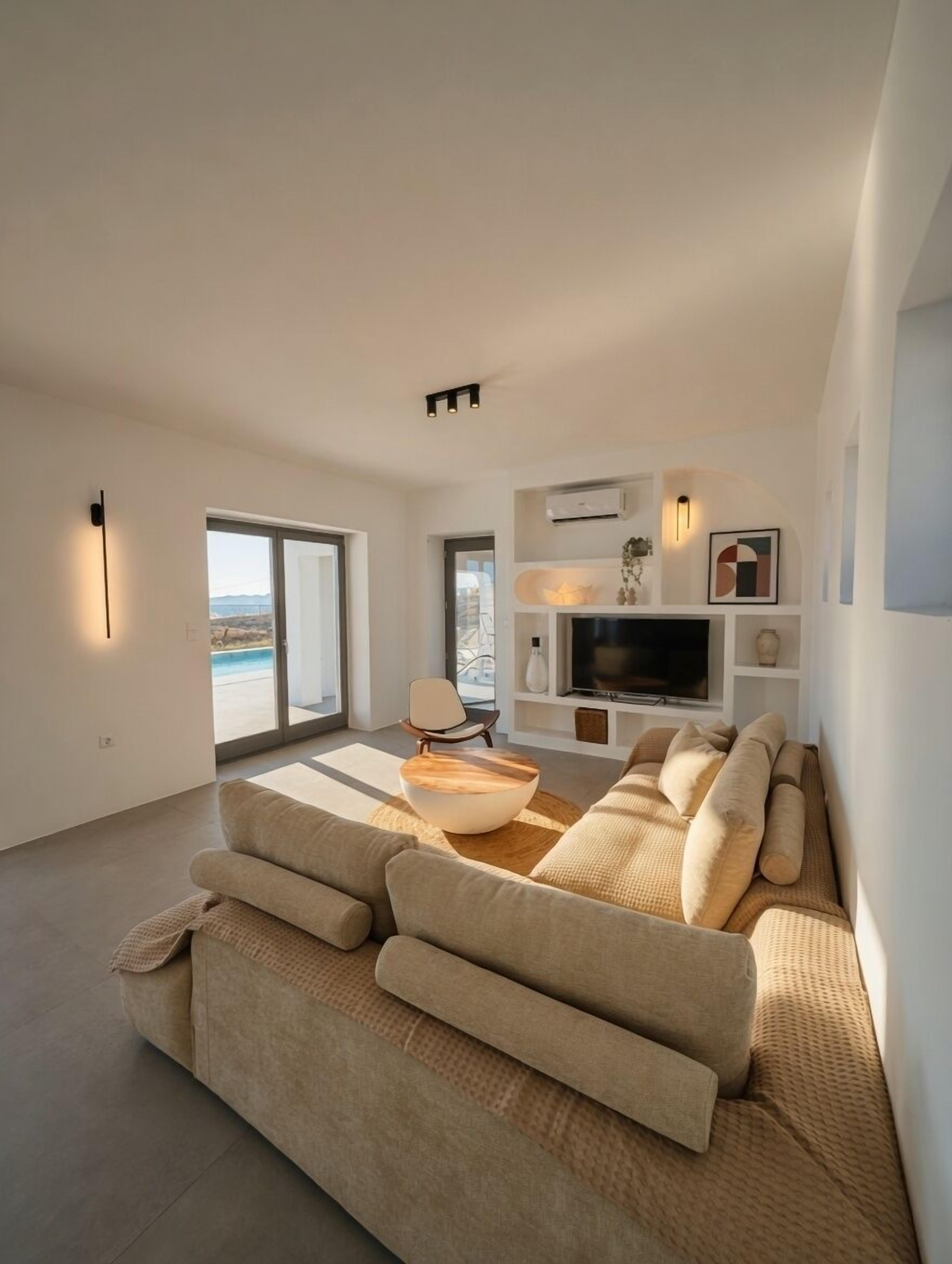 Ein modernes Wohnzimmer mit einer großen Couch, einem Couchtisch, einem Fernseher und einem Kamin.
