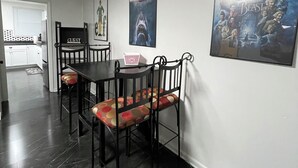 Ein Essbereich mit einem schwarzen Tisch und Stühlen, einem Schild mit der Aufschrift 'Guest' und Filmplakaten an der Wand.