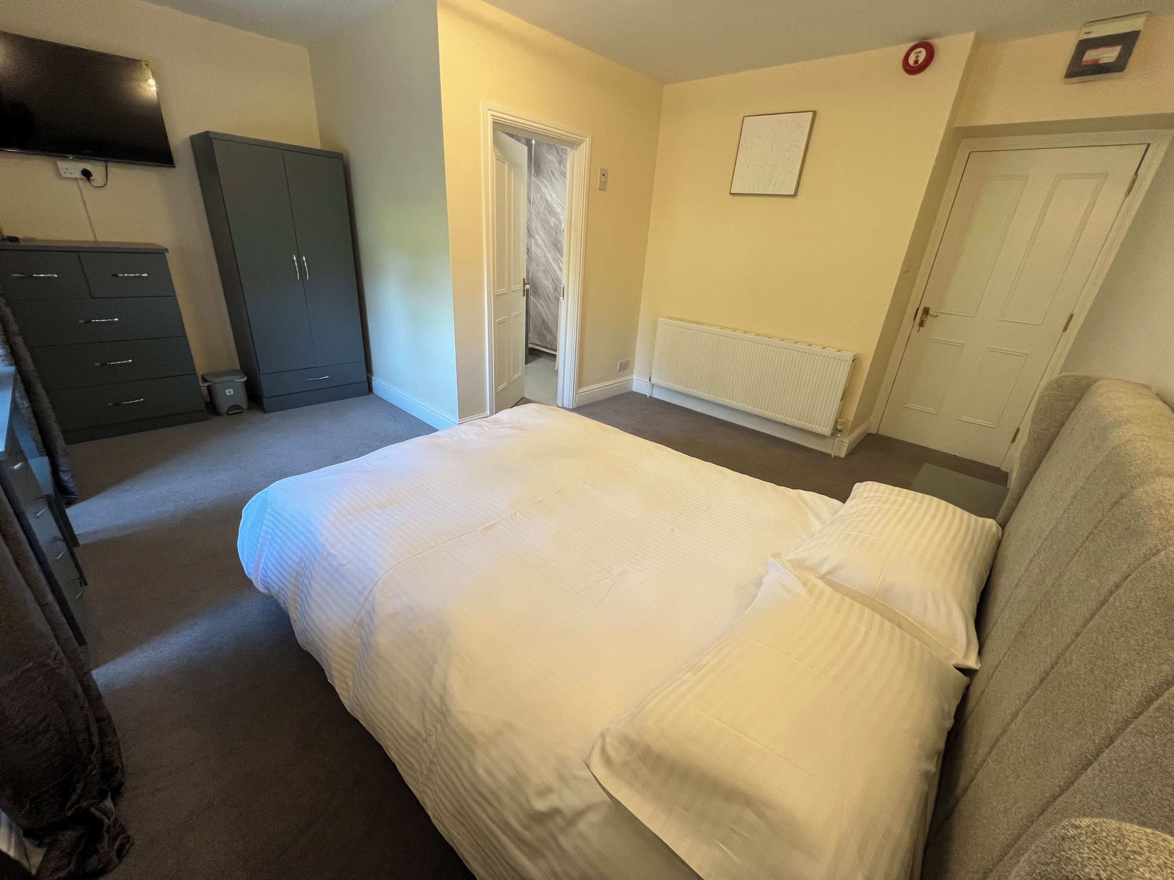 Une chambre à coucher avec un lit, une armoire, un radiateur et une porte.