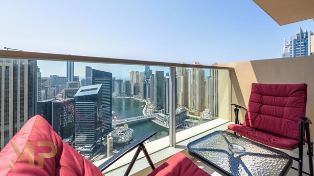 A balcony with a city view, red chairs, and a glass table. - Marco Polo - Chic 1BR in Marina Hub | Expansive Balcony (Dubai)