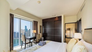 A hotel room with a large bed, a desk with a chair, a view of the city, and a dark-colored wardrobe. - Marco Polo - Chic 1BR in Marina Hub | Expansive Balcony (Dubai)
