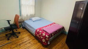Une chambre avec un lit, un bureau, une chaise et une armoire.