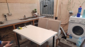 Une petite cuisine équipée d’un évier, d’un lave-linge et d’une table.