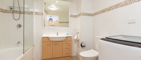 A modern bathroom with a glass shower enclosure, a wooden vanity with a sink, and a toilet.