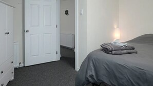 Un dormitorio con cama, armario, puerta y radiador.