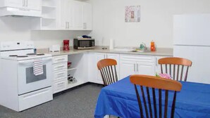 A compact kitchen with white cabinets, a microwave, a stove, and a table with chairs.