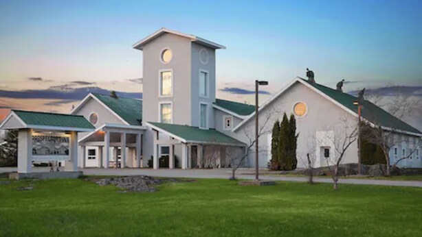 A modern building with a central tower, multiple entry points, and a well-maintained lawn.
