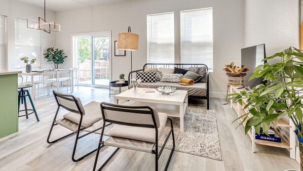 A modern living space with a dining area, sofa, and large windows. - Stylish OKC Duplex 2bed 2.5bath Unit B (Oklahoma City)